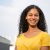 Attractive young woman smiling at camera. Portrait of beautiful cheerful young woman in yellow t-shirt standing on street and smiling at camera. Emotion concept